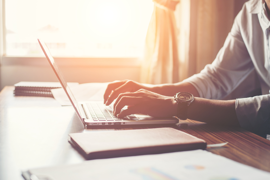 Close de mãos digitando em um notebook.