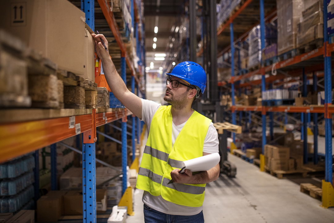 Profissional com prancheta e caneta na mão realizando o controle de estoque.