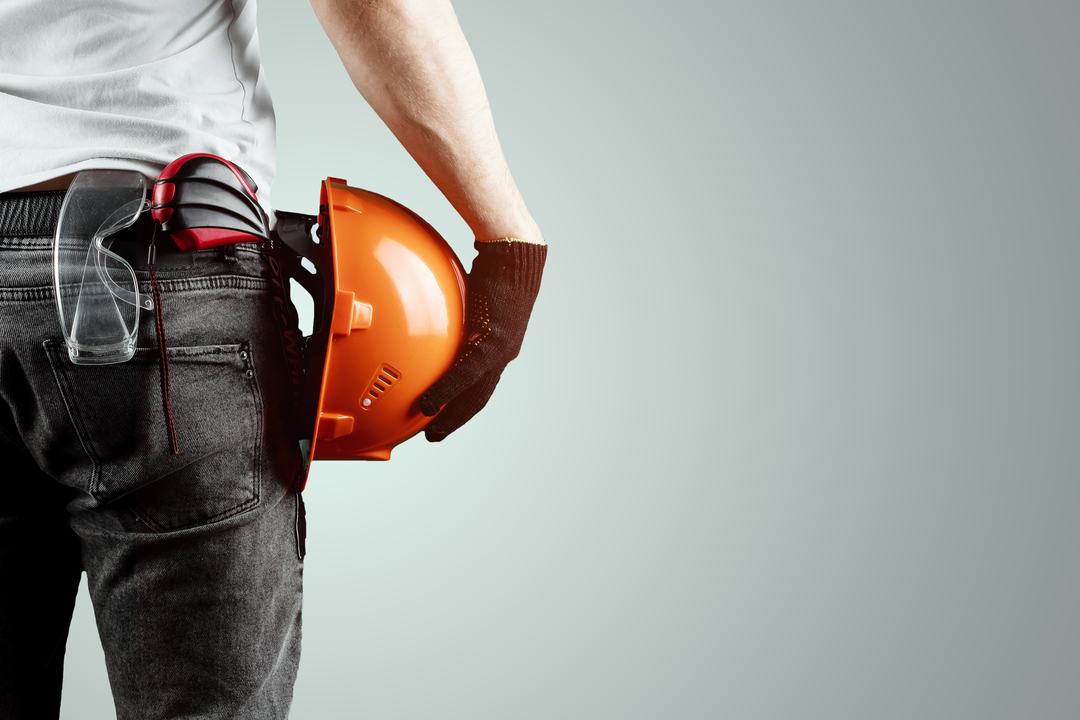 Profissional segurando capacete com óculos de proteção no bolso, representando os tipos de manutenções.